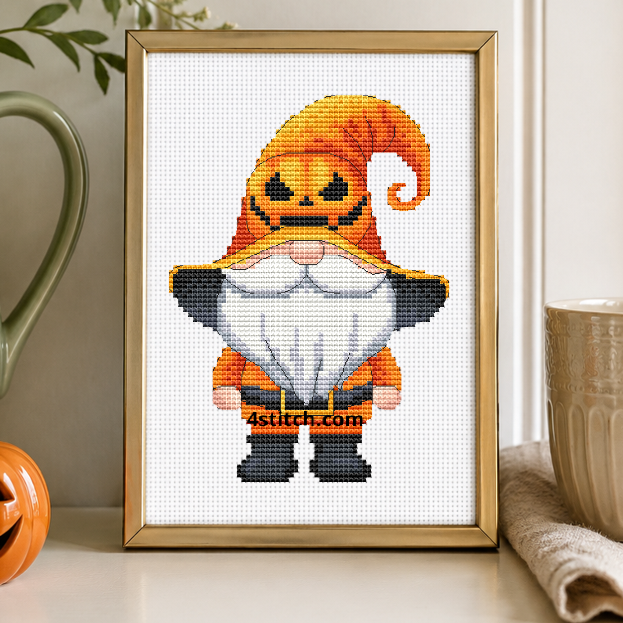 Jack-o'-Lantern Hat Gnome on white Aida in a small frame, photographed close up in a bright cozy autumn interior