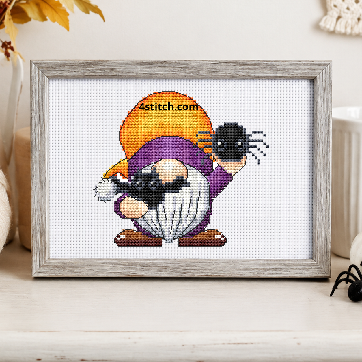 Spider Halloween Gnome on white Aida in a small frame, photographed close up in a bright cozy autumn interior