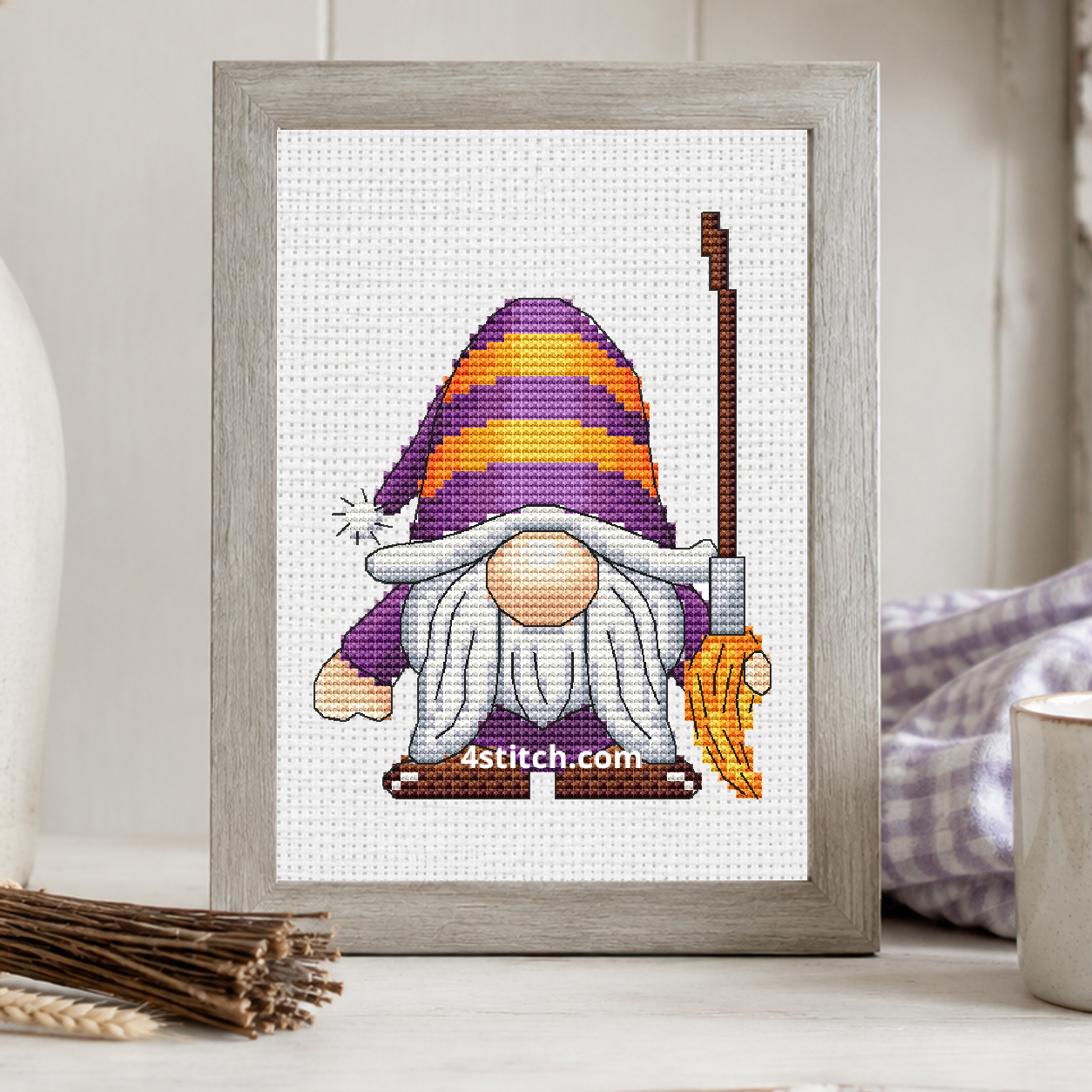 Striped Hat Broom Gnome on white Aida in a small frame, photographed close up in a bright cozy autumn interior