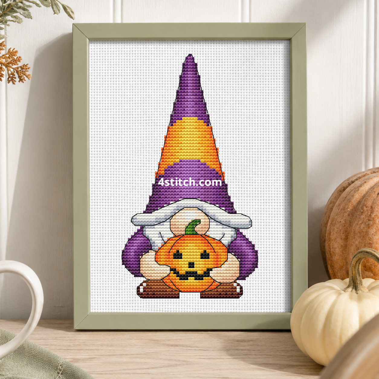 Pumpkin Hug Halloween Gnome on white Aida in a small frame, photographed close up in a bright cozy autumn interior