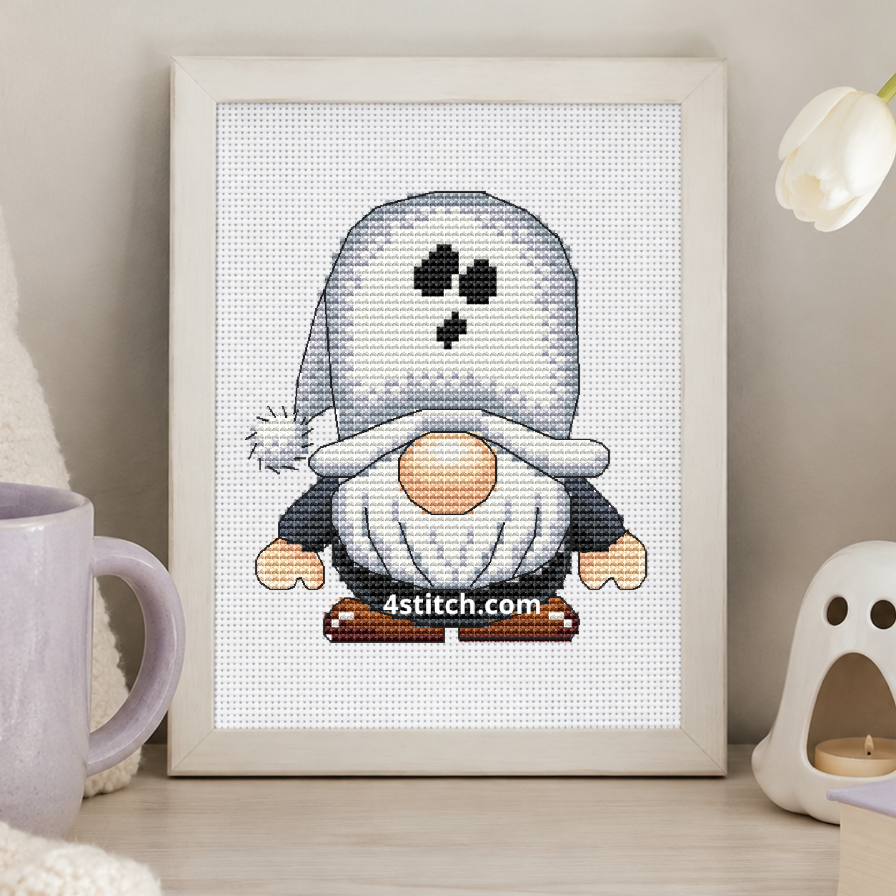 Ghost Hood Halloween Gnome on white Aida in a small frame, photographed close up in a bright cozy autumn interior