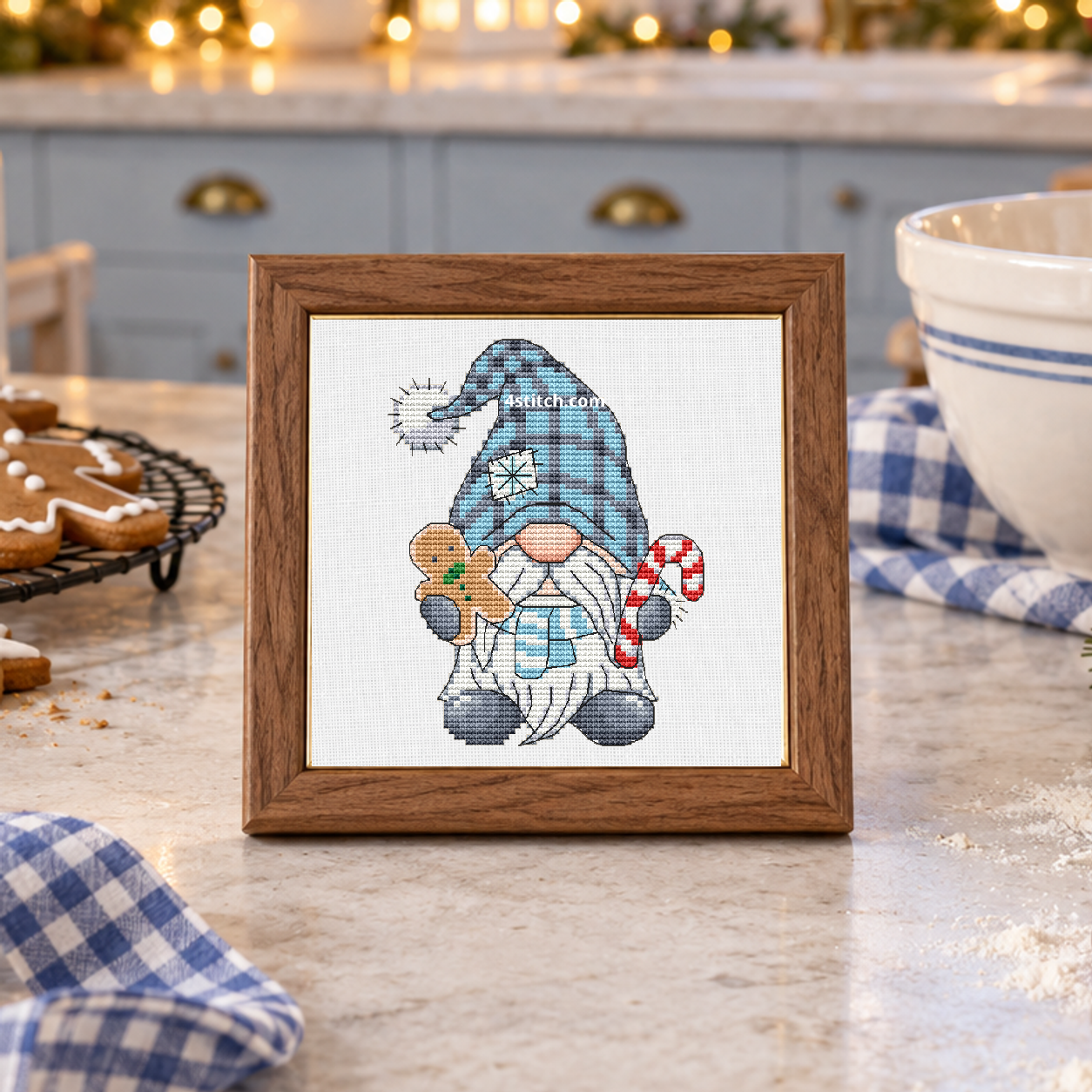Gingerbread and Candy Cane Winter Gnome, featuring a blue-hatted gnome holding a gingerbread cookie and a candy cane, on white Aida in a small tabletop frame in a cheerful blue-and-ivory Christmas baking kitchen.