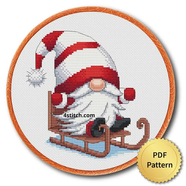 Sledding Christmas Gnome Cross Stitch Pattern shown as finished cross stitch in an embroidery hoop with a gold PDF Pattern medal.