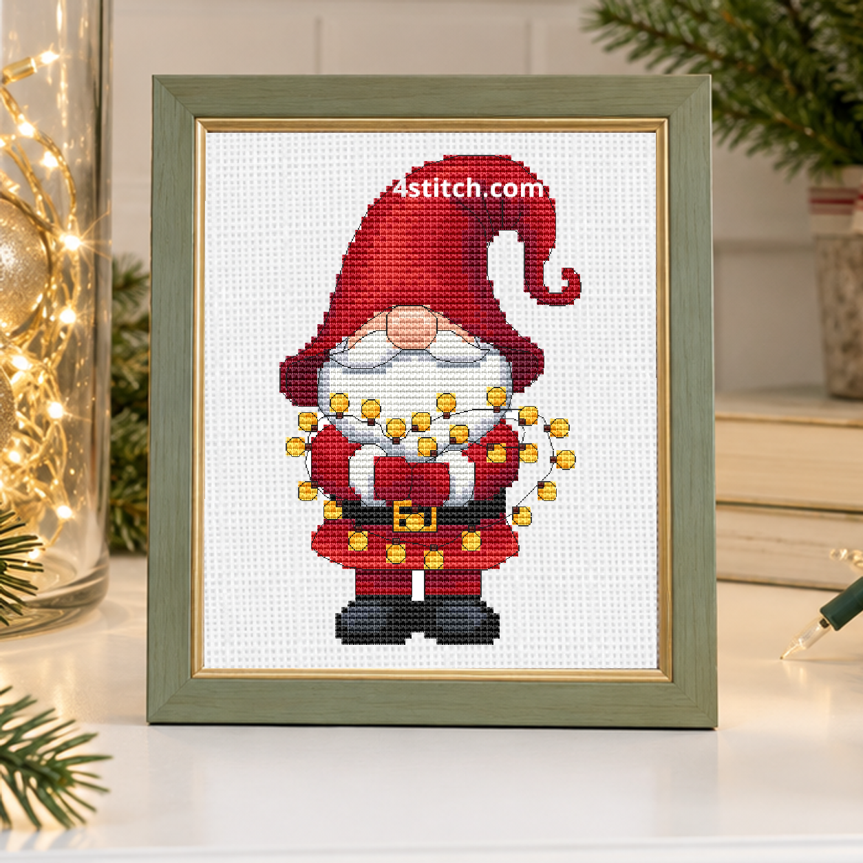 Close-up of Christmas Lights Santa Gnome on white Aida in a sage-and-gold frame on a light Christmas decorating console.
