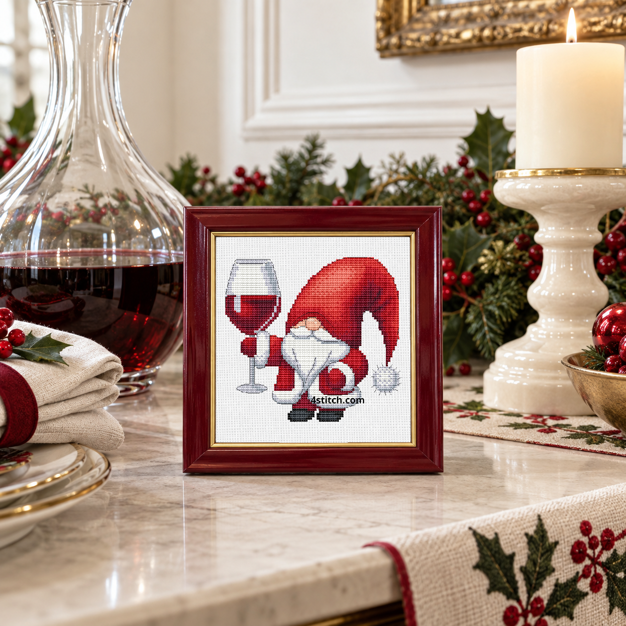 Wider interior view of Christmas Toast Santa Gnome on white Aida in a burgundy-and-gold frame on a sunlit Christmas dining sideboard, with the small frame resting among coordinating Christmas decorations.