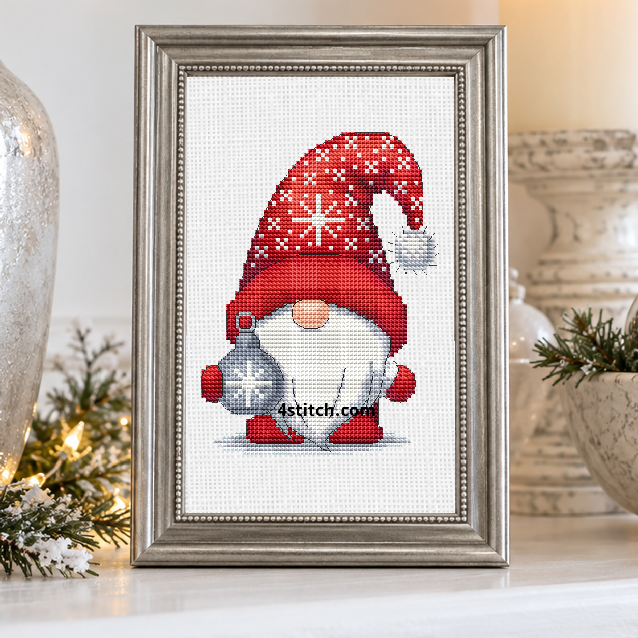 Close-up of Silver Snowflake Bauble Gnome on white Aida in a pewter-silver frame on a bright white winter mantel.