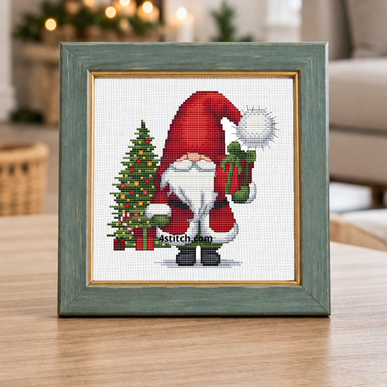Close-up of Christmas Tree Gift Gnome on white Aida in a muted teal frame on a bright festive living-room console.