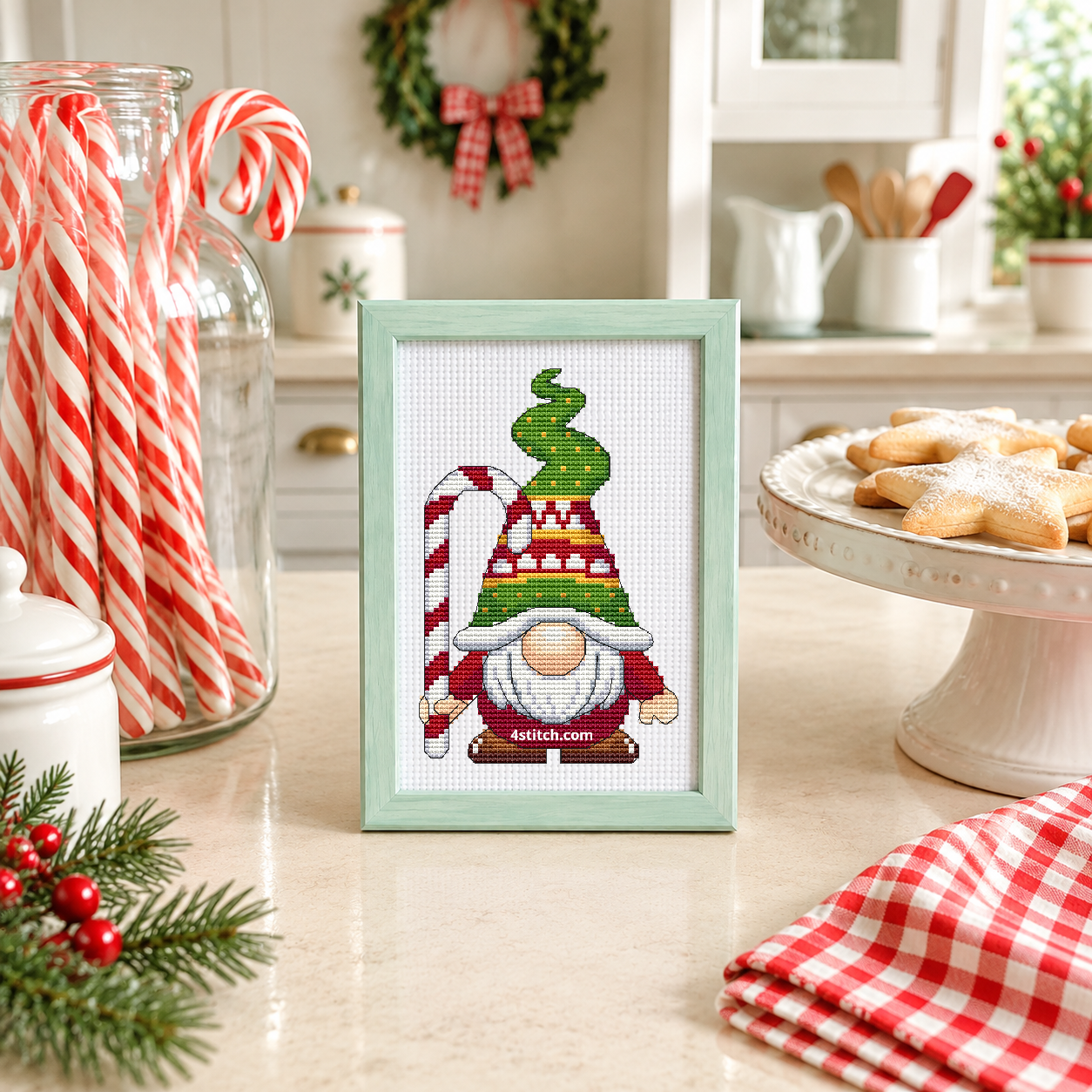 Candy Cane Tree Hat Gnome with a red-and-white candy cane and a curling green Christmas-tree hat, on white Aida in a mint green frame in a bright Christmas bakery with candy canes and star biscuits.