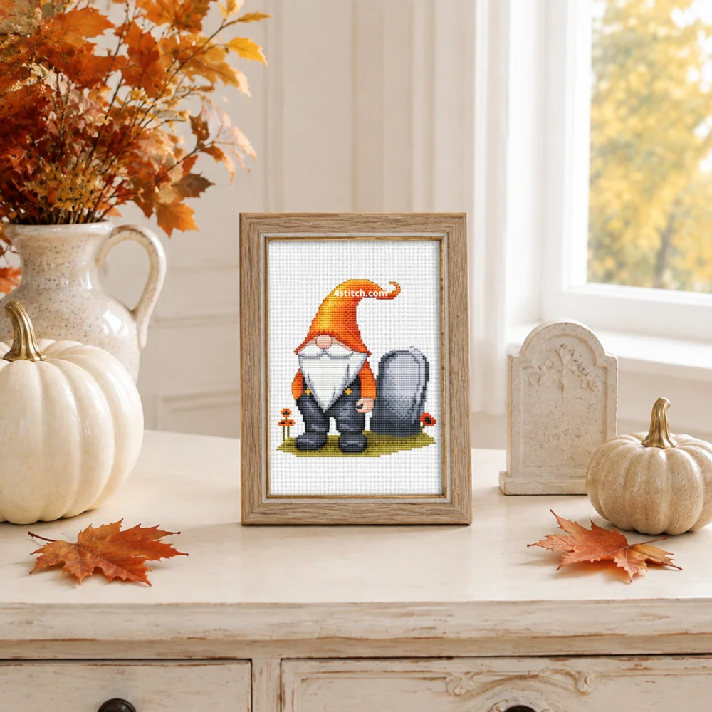 Framed Orange Hat Graveyard Gnome cross stitch on white Aida in a bright autumn Halloween interior