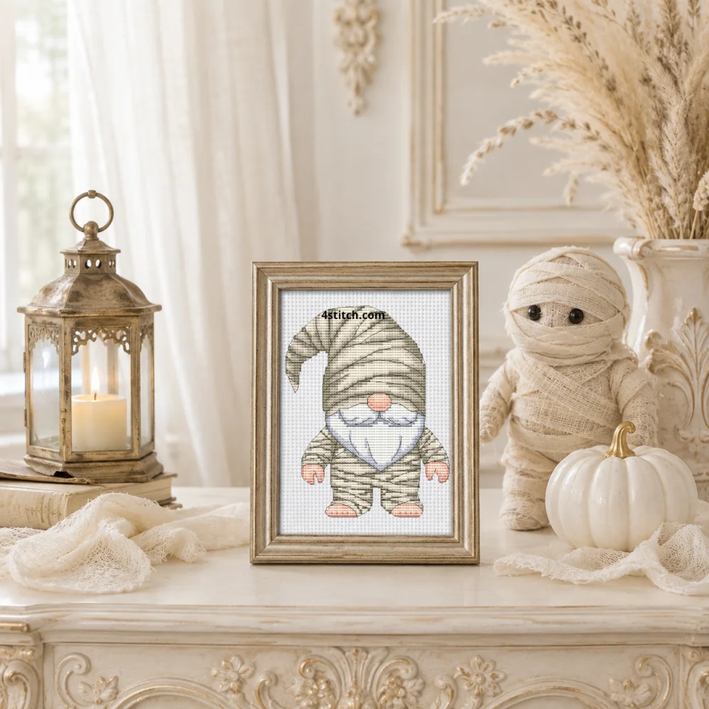 Framed Mummy Halloween Gnome cross stitch on white Aida in a bright sandy Halloween interior