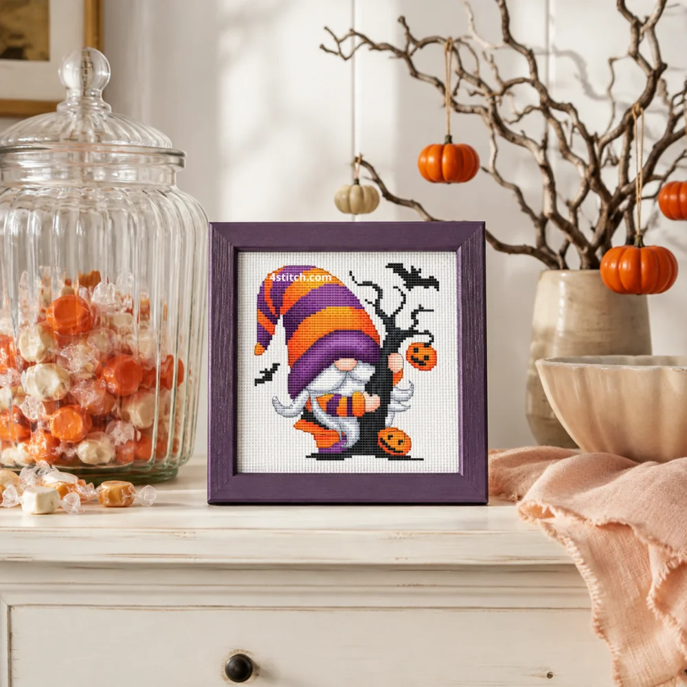 Small framed Candy and Pumpkin Halloween Gnome on white Aida in a bright themed interior, with the complete original motif and its 4stitch.com watermark.