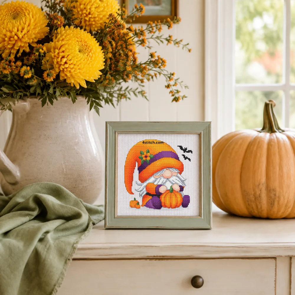 Small framed Pumpkin Flower Halloween Gnome on white Aida in a bright themed interior, with the complete original motif and its 4stitch.com watermark.