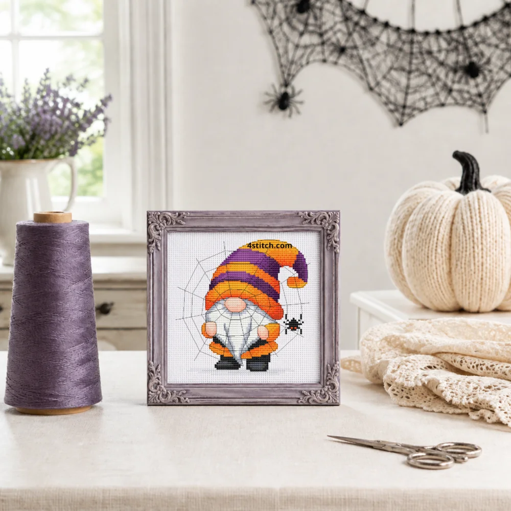Small framed Spiderweb Hat Halloween Gnome on white Aida in a bright themed interior, with the complete original motif and its 4stitch.com watermark.