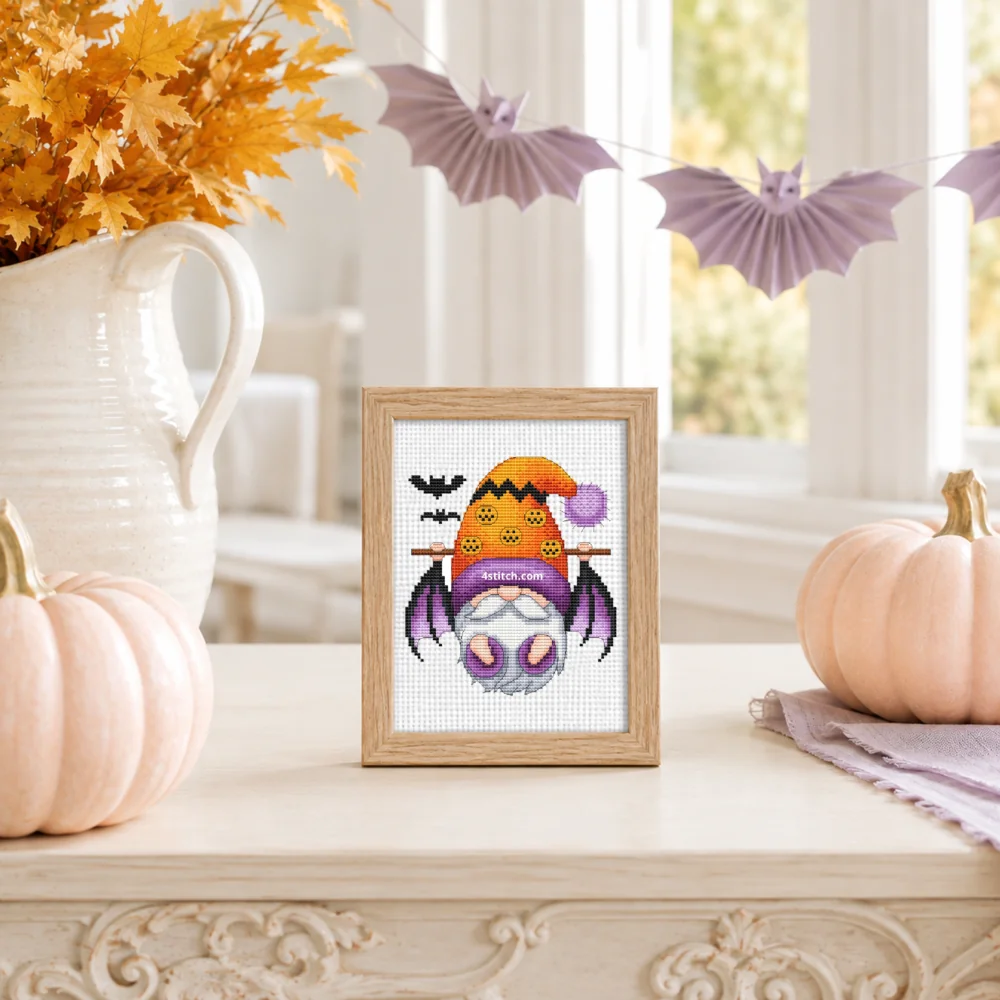 Small framed Bat-Wing Pumpkin Halloween Gnome on white Aida in a bright themed interior, with the complete original motif and its 4stitch.com watermark.