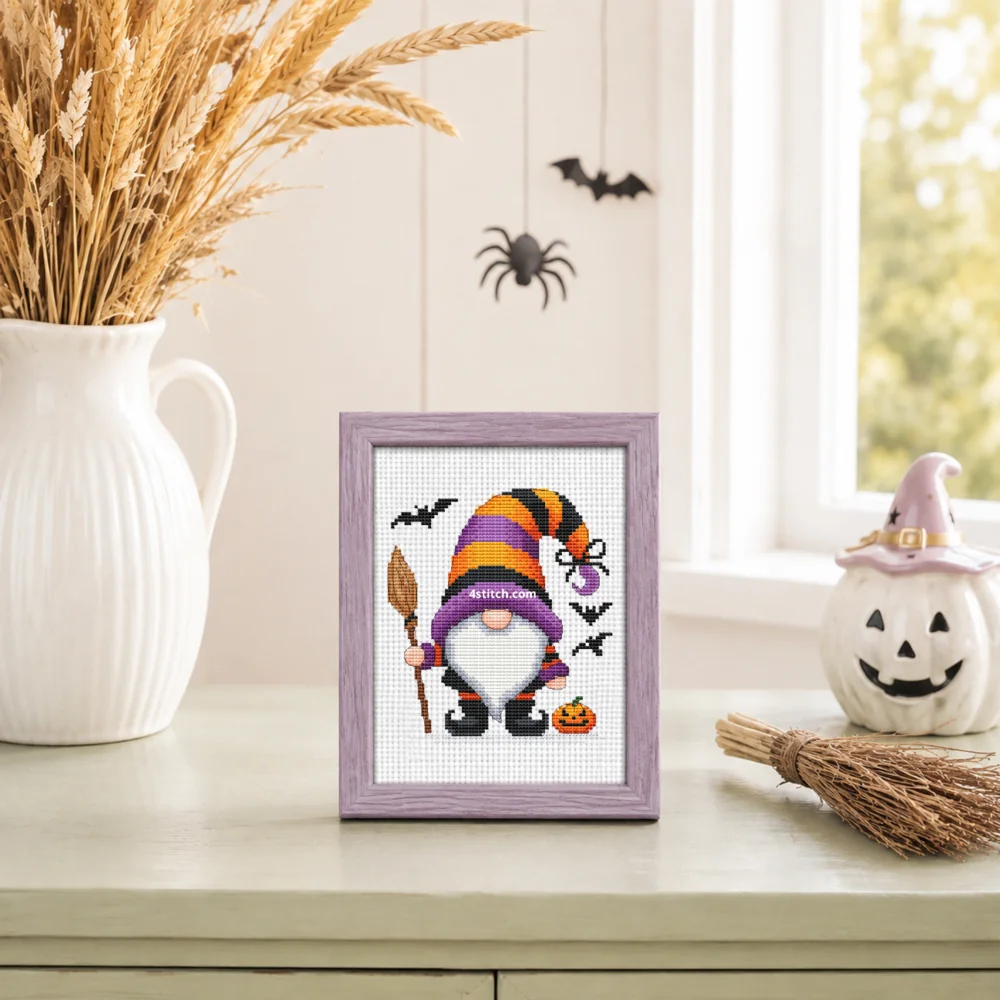 Small framed Broom and Spider Witch Gnome on white Aida in a bright themed interior, with the complete original motif and its 4stitch.com watermark.