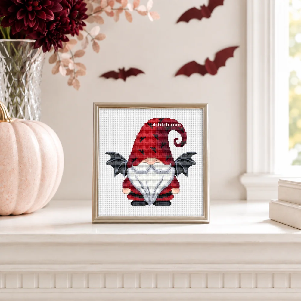 Bat Wing Halloween Gnome Cross Stitch Pattern shown as a small framed embroidery on white Aida in a bright Halloween interior.