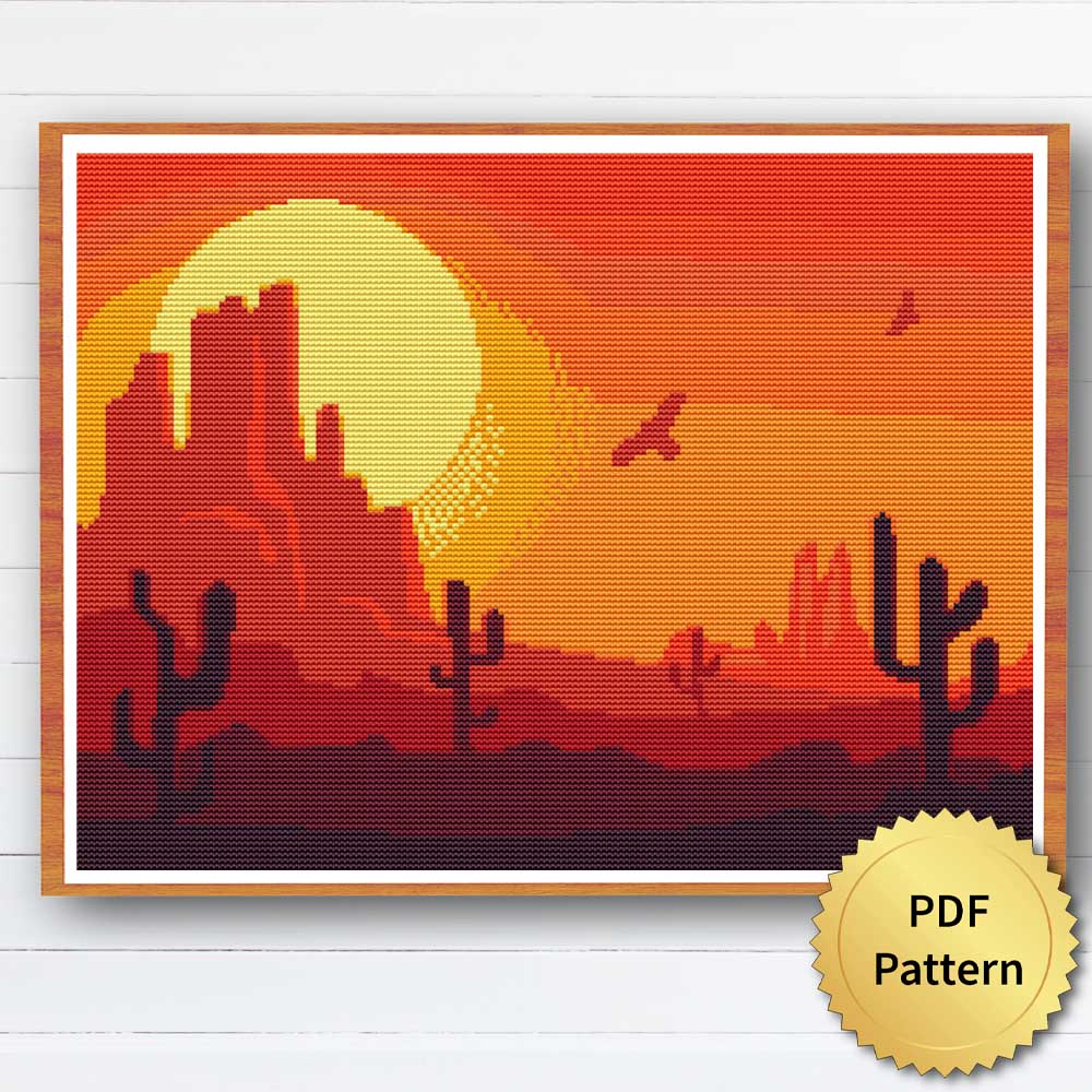 Cross stitch pattern featuring a desert landscape with sand dunes, cacti, and mountains in the distance