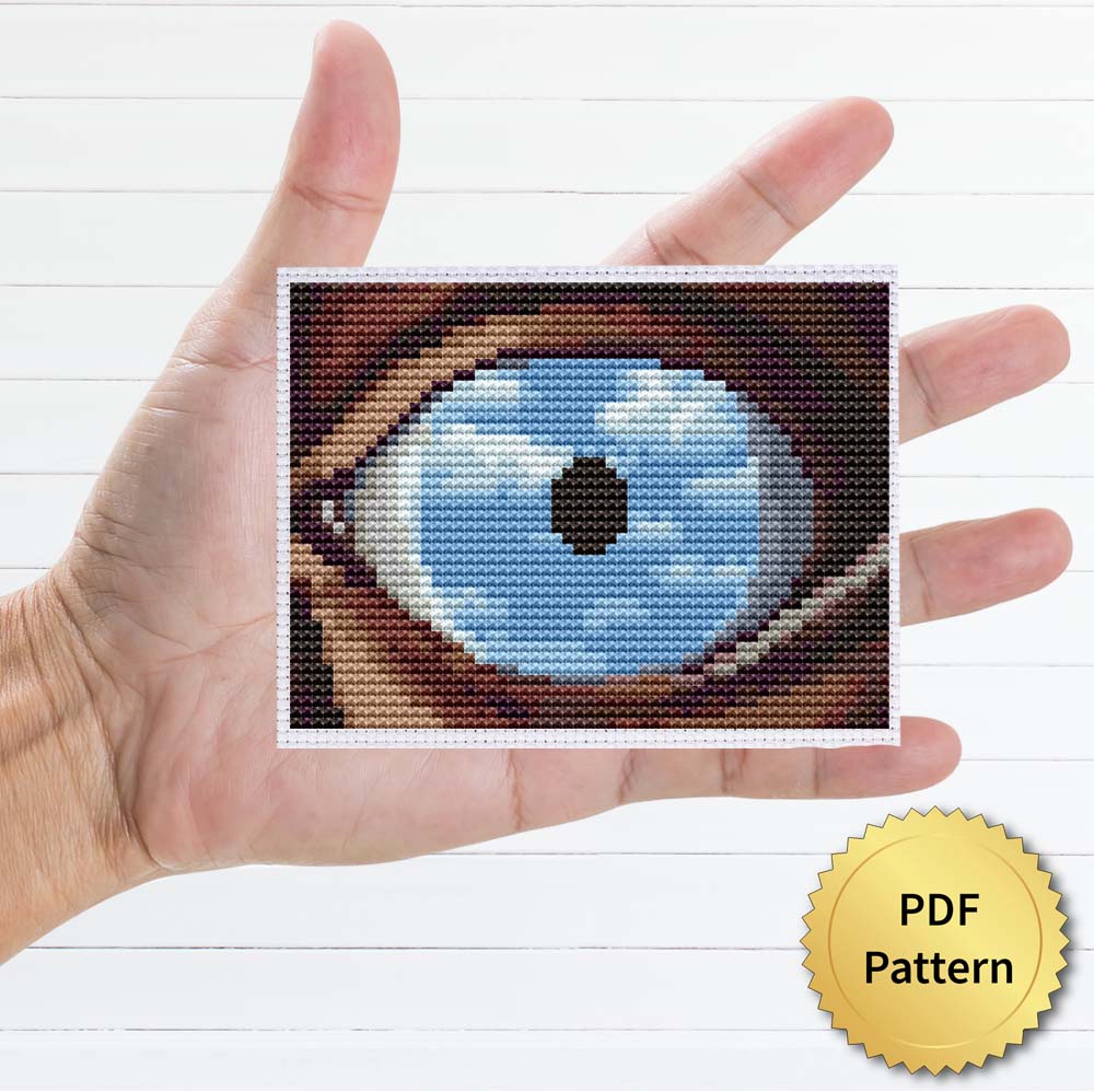 The False Mirror cross stitch pattern featuring a beautiful reproduction of the famous Rene Magritte