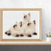 A cross stitch pattern featuring three cute white kittens cuddling together